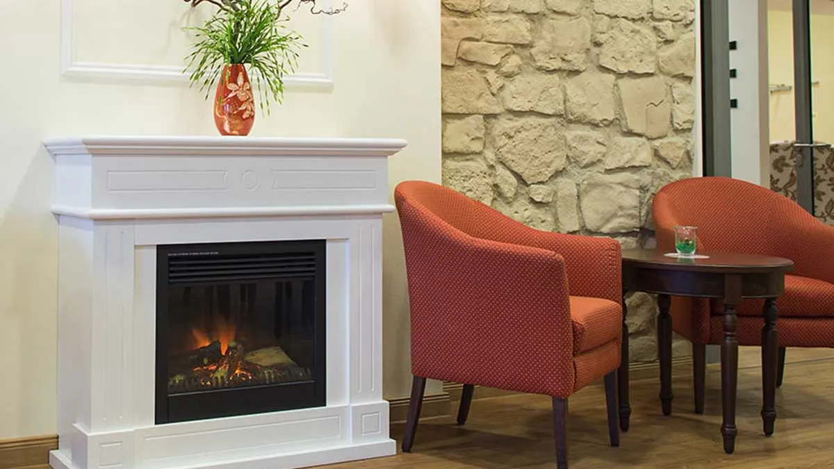 Sitzgruppe mit roten Sesseln und kleinem Tisch neben einem Kamin im PFLEGEN & WOHNEN HAMBURG Farmsen.