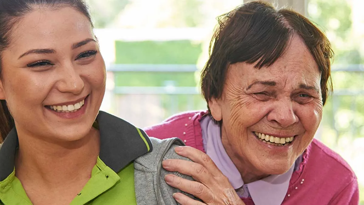 Bewohnerin des PFLEGEN & WOHNEN HAMBURG-Standorts Marienthal lacht gemeinsam mit Pflegerin.