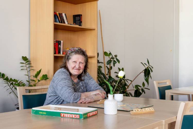 Ramona Lehmann im Aufenthaltsraum am Tisch bei PFLEGEN & WOHNEN HAMBURG, hat am Standort Öjendorf ihr Zuhause gefunden.