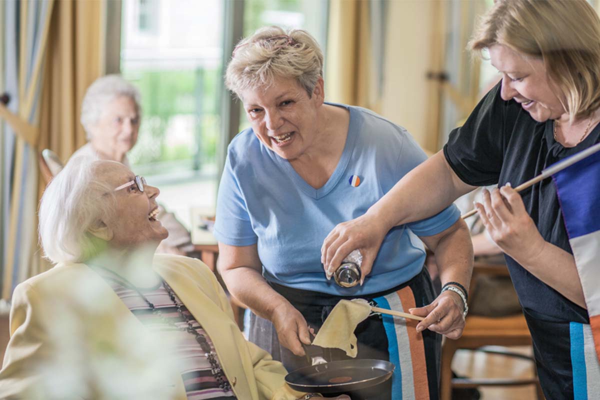 Im Gemeinschaftsraum von PFLEGEN & WOHNEN HAMBURG treffen sich Senior:innen zum gemeinsamen Kochen mit dem Küchenteam.