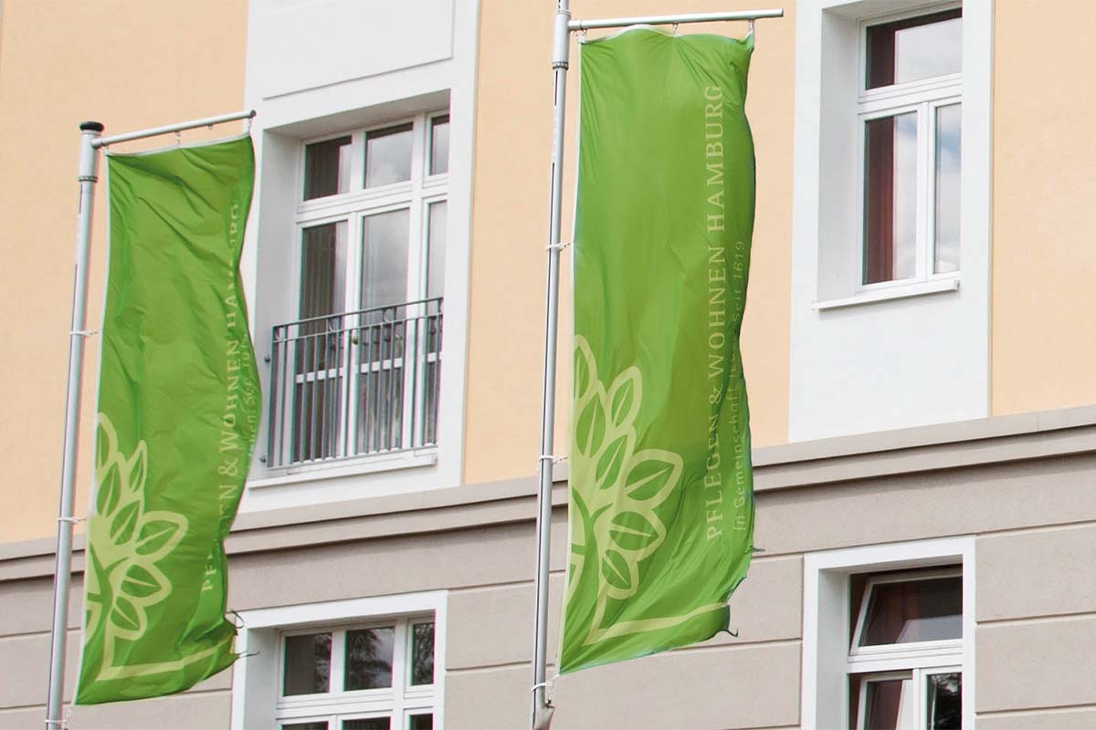Am Hauptsitz von PFLEGEN & WOHNEN HAMBURG begrüßen wehende Fahnen Besucher und Mitarbeitende.